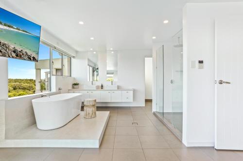 a white bathroom with a tub and a large window at Saltwater, Sunrise Beach in Sunrise Beach