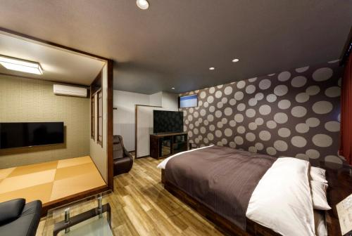 1 dormitorio con 1 cama y TV de pantalla plana en HOTEL HanaBi 長良の湯 -大人専用-, en Gifu
