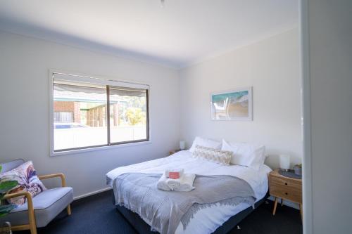 ein Schlafzimmer mit einem Bett, einem Fenster und einem Stuhl in der Unterkunft Lakeside dream in Swansea