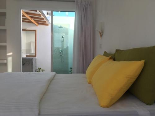 Vaali Maldives Island Escapes & Dive في فيليدهو: غرفة نوم بسرير ابيض مع مخدات صفراء