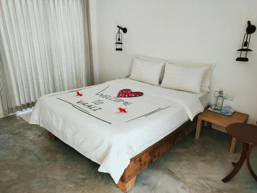 Una cama con un edredón blanco con flores rojas. en Vaali Maldives Island Escapes & Dive, en Felidhoo