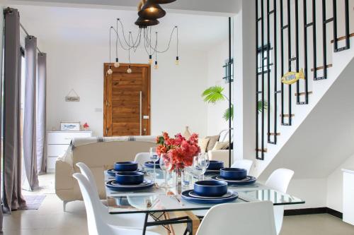 a dining room with a table and white chairs at Villa Grain de café, 3 chambres piscine accès plage in Trou aux Biches