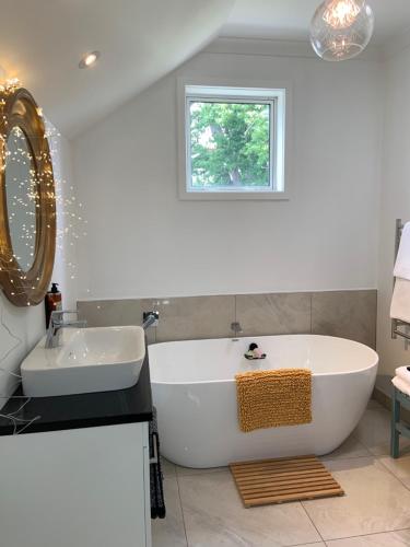 a white bathroom with a tub and a sink at The Greytown Loft in Greytown