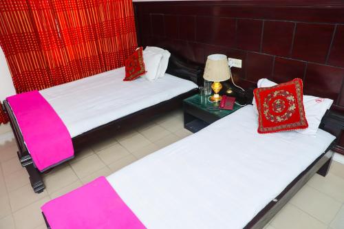 two beds in a hotel room with red and white pillows at Ali International Hotel in Dhaka