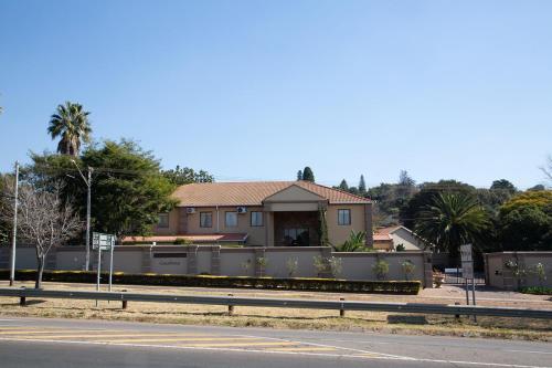 a house with a fence in front of a street at Constantia Manor Guest House in Pretoria