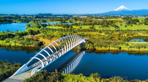 a bridge over a river with a mountain in the background at Parkside Motel and Apartments in New Plymouth