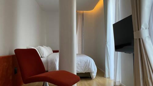 チェンマイにあるThe Sayla hotel(Baan Sayla)のベッドルーム1室(ベッド1台、赤い椅子付)