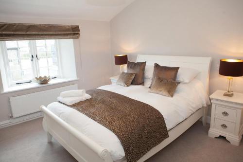 a bedroom with a white bed and two windows at Roundton House in Chirbury