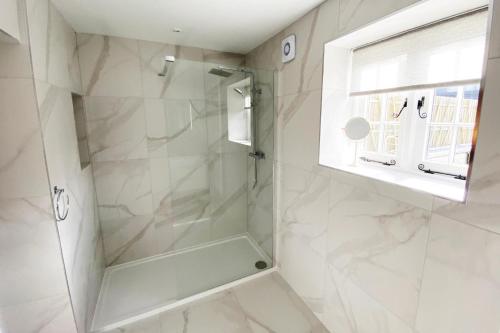 a white bathroom with a shower and a window at Roundton House in Chirbury