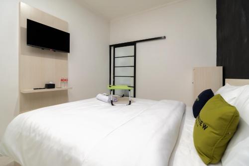 a bedroom with a white bed and a tv on the wall at Urbanview Hotel Bizhome Artha Gading Boulevard by RedDoorz in Jakarta