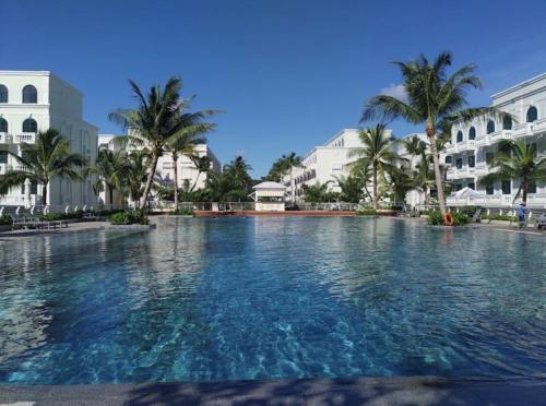 a large swimming pool with palm trees and buildings at Myrtle Boutique Hotel Phu Quoc in Phu Quoc