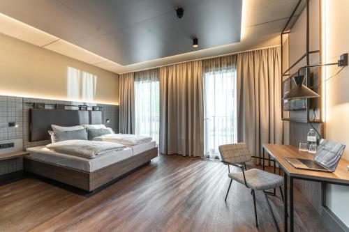 a bedroom with a bed and a desk with a laptop at FreshSuites & Bar in Dachau