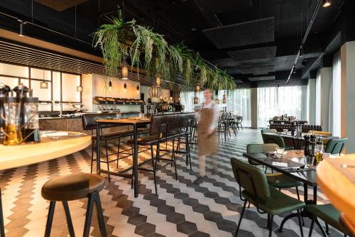 a person standing in a restaurant with tables and chairs at FreshSuites & Bar in Dachau