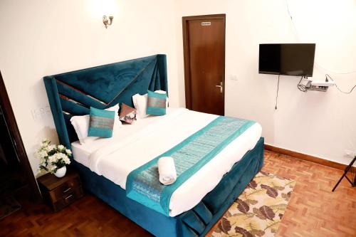 a bedroom with a blue and white bed with a television at Fortune Home Service Apartment 3Bhk,E-28 Saket 1B in New Delhi