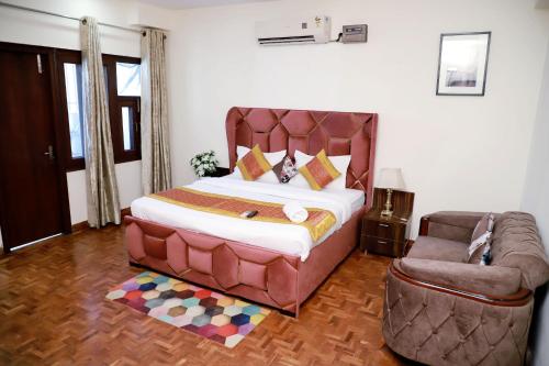 a bedroom with a large bed and a chair at Fortune Home Service Apartment 3Bhk,E-28 Saket 1B in New Delhi