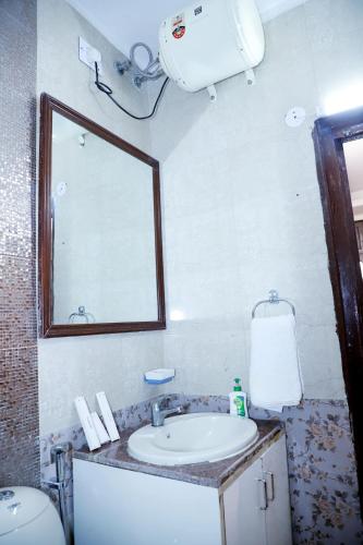 a bathroom with a sink and a mirror and a toilet at Fortune Home Service Apartment 3Bhk,E-28 Saket 1B in New Delhi