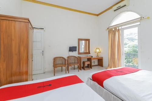 a bedroom with two beds and a desk and a window at RedDoorz at Villa Puncak Tidar in Malang