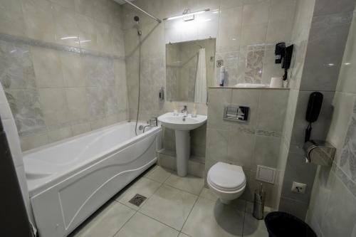 a bathroom with a sink and a tub and a toilet at BANQUETING & GUEST HOUSE ПОМЕСТЬЕ in Kostanay