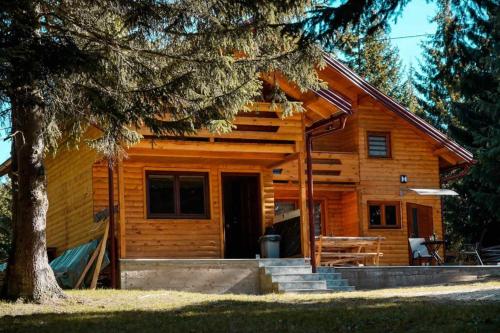 a log cabin with a porch and a tree at Ski Chalet Jahorina in Jahorina