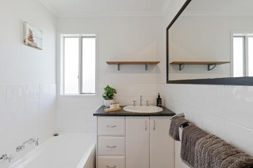 a white bathroom with a sink and a bath tub at Island Getaway Cape Woolamai in Cape Woolamai