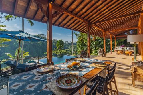 uma sala de jantar exterior com uma mesa e uma piscina em Ubud Valley Boutique Resort em Ubud