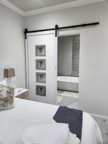 a white bedroom with a bed and a bath tub at Caribbean Estates Villa Raiya- First choice !!! 4 bedrooms with ensuite bathrooms in Port Edward