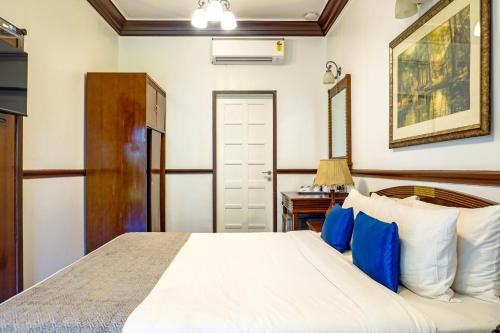 a bedroom with a bed with blue and white pillows at Citrus Chambers Mahabaleshwar in Mahabaleshwar