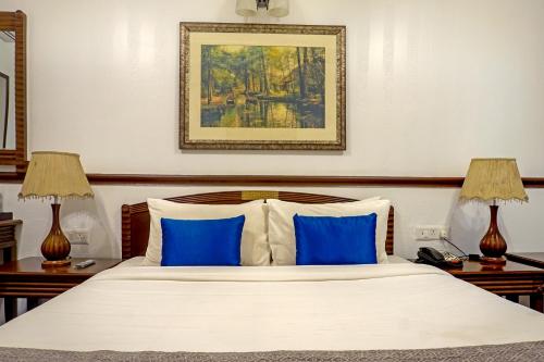 a bedroom with a large bed with blue pillows at Citrus Chambers Mahabaleshwar in Mahabaleshwar