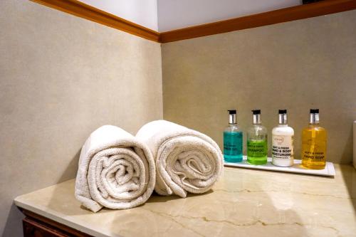 a bathroom with towels on a counter with bottles of alcohol at Citrus Chambers Mahabaleshwar in Mahabaleshwar