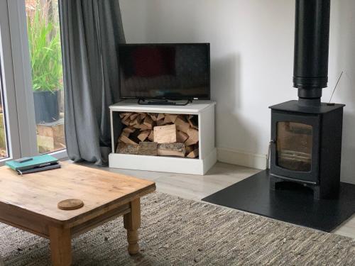 a living room with a fireplace and a wood stove at Seaglass Cottage, 5 mins from beach, hot tub on request in South Hayling