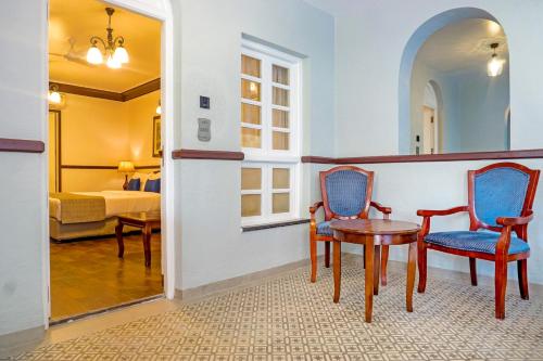 a room with two chairs and a table and a bed at Citrus Chambers Mahabaleshwar in Mahabaleshwar