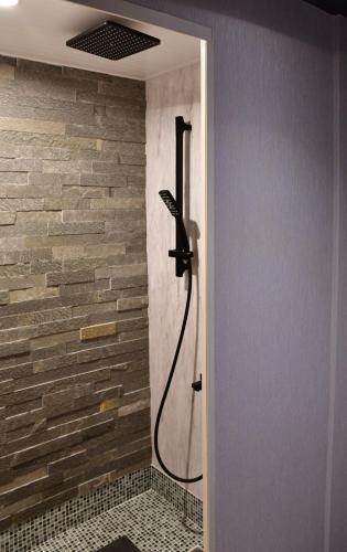 a shower in a bathroom with a stone wall at Villa 33 Kashikojima in Ugata