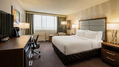 a hotel room with a bed and a desk at Holiday Inn Winnipeg-South by IHG in Winnipeg