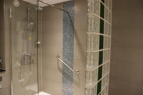 ducha con puerta de cristal y separador de vidrio en Holiday Inn Huntingdon Racecourse, an IHG Hotel, en Huntingdon