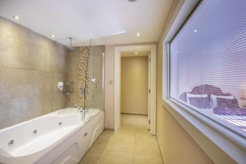 a bathroom with a tub and a sink and a window at Han Deluxe Hotel in Oludeniz