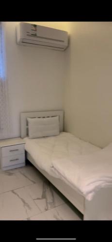 a white bed in a room with a white wall at Altaraf Resort in Al Shafa