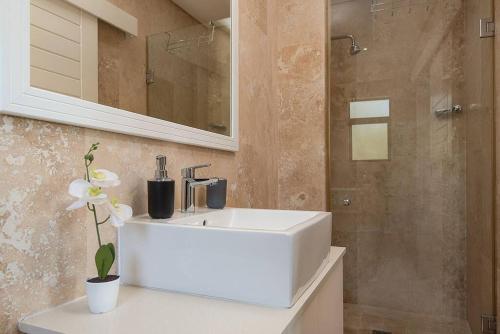 uma casa de banho com um lavatório branco e um chuveiro em 9 On Crystal Cove 5 Bedroom Townhouse in Zimbali em Ballito