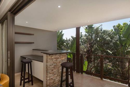 uma cozinha com um bar com bancos e uma varanda em 9 On Crystal Cove 5 Bedroom Townhouse in Zimbali em Ballito