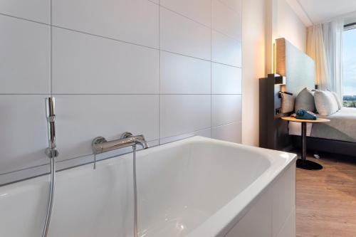 a white bathroom with a tub and a bed at INNSiDE by Meliá Amsterdam in Amsterdam