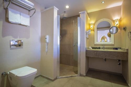 a bathroom with a shower and a toilet and a sink at Han Deluxe Hotel in Oludeniz