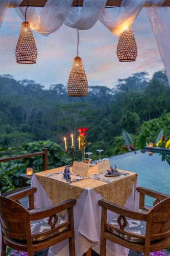 a table with two chairs and a view of a pool at Ubud Valley Boutique Resort in Ubud