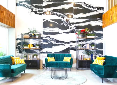 a lobby with two green chairs and a black and white wall at Sann Hotel in Chiang Rai
