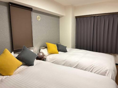 um quarto de hotel com duas camas com almofadas amarelas em LIT’S INN Sapporo em Sapporo