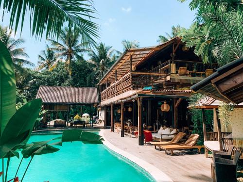 een resort met een zwembad naast een gebouw bij De Ubud Villas & Spa in Ubud