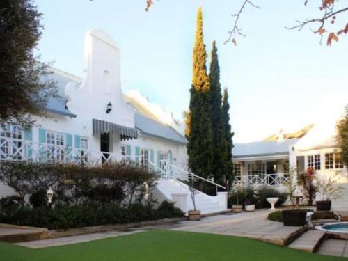a large white house with a lawn in front of it at La Belle Guest House in Bloemfontein