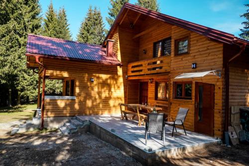 a wooden cabin with a table and chairs on a deck at Ski Chalet Jahorina in Jahorina