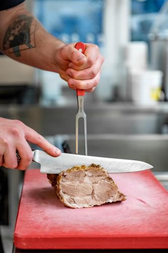 a person holding a knife and fork over a piece of meat at Hotel Grauer Bär in Sölden