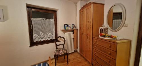 Zimmer mit einer Kommode, einem Spiegel und einem Stuhl in der Unterkunft Casa della Rosina in Bresimo