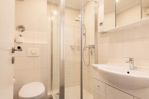 ein Bad mit einer Dusche, einem WC und einem Waschbecken in der Unterkunft Rosenwall, App 14 in Wenningstedt-Braderup