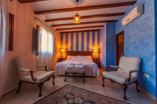 1 Schlafzimmer mit einem Bett und 2 Stühlen in der Unterkunft Boutique hotel El Capricho in Beniali